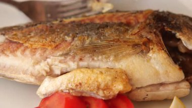 Kıyıdaki taze sebzelerle tamamlanmış lezzetli bir balık yemeğinin tadını çıkarın..