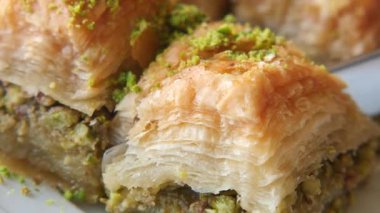 Baklava ustalıkla dilimlenip zengin fındık dokusunu ortaya çıkarırken izleyin..