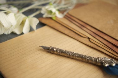 Çiçek elementleri ve zarflarla bir masanın üzerine yerleştirilmiş hassas yazma araçları.