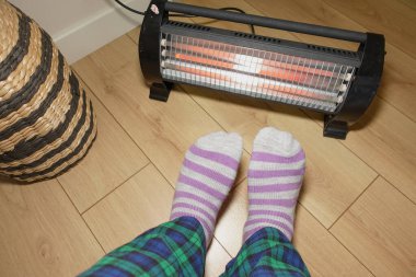 Çizgili çoraplar sıcak, ahşap bir zeminde, sıcak bir ısıtıcının yanında dinlenir..