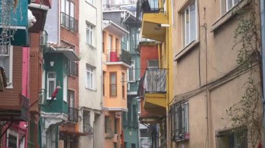 Dar bir şehir sokağındaki tuhaf renkli binalara yağmur damlaları yağıyor..