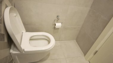 Basit bir tuvalet tasarımı ve fayanslı duvarları olan temiz bir tuvalet..