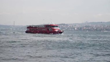 Renkli bir tekne, İstanbulların ufuk çizgisini gösteren Boğaz 'da geziniyor..