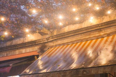 Telli ışıklardan gelen yumuşak ışık, açık hava kafeteryasını aydınlatıyor..