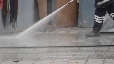 Bir işçi şehirdeki beton bir bölgeyi temizlemek için elektrikli çamaşır makinesi kullanıyor..