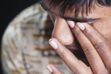 Genç bir birey derin düşüncelere dalmış ellerini yüzlerine koyuyor..