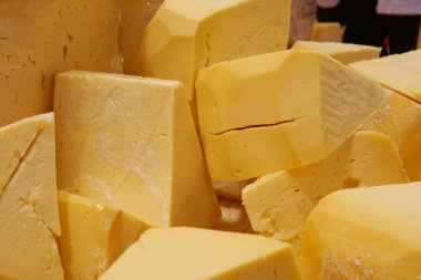 Yerel bir markette müşteriler için yığılmış taze çedar peyniri blokları.