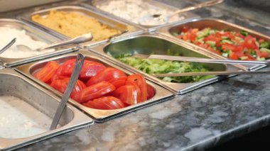 Renkli sebzeler ve sargılar hareketli bir yemek barında bekliyor..