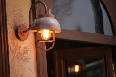 Yumuşak ışık, kapı eşiğine monte edilmiş klasik tarzda bir demirbaş ile parlar..