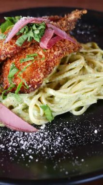 Lezzetli bir tabak çıtır tavuğun tadını çıkarın kremalı makarnanın üzerinde otlarla servis ediliyor..