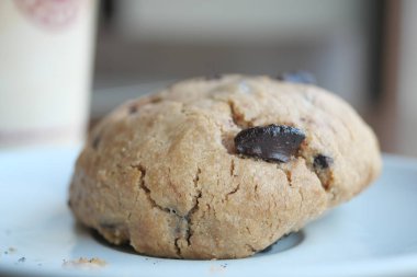 Büyük, lezzetli bir kurabiye bir içeceğin yanındaki tabakta duruyor..