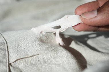 Bir insan dikkatlice bir kumaş parçasından sakız çıkarıyor..
