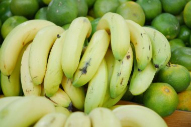 Bir markette canlı yeşil limonların yanında bir muz kümesi yatıyor..