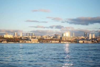 İstanbul 'un silueti, güneş suyun üzerinde batarken ışıldıyor.