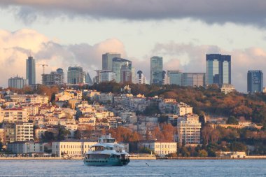 İstanbul semalarında alacakaranlıkta yükselen feribotla birlikte bir feribot su üzerinde yol alır..