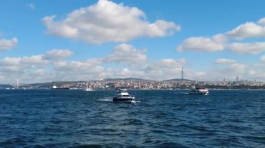 Tekneler İstanbul 'un sularında bulutlu açık mavi bir gökyüzünün altında geziniyor..