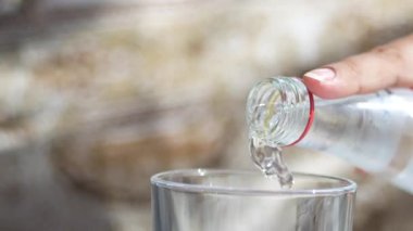 Bir el, şişeden taze suyu boş bir bardağa doldurur..