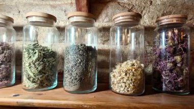 Raftaki cam kaplarda çeşitli kurutulmuş bitkiler düzenlenir..