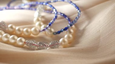 İncilerin ve boncukların narin iplikleri lüks kumaşların üzerinde duruyor..