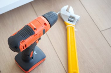 Tamir sırasında ahşap zemine yerleştirilmiş bir matkap ve İngiliz anahtarı..