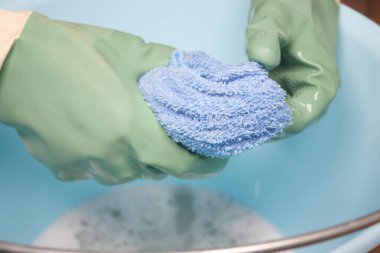 Eldivenli eller leğende mavi bir bez çıkartıyor..