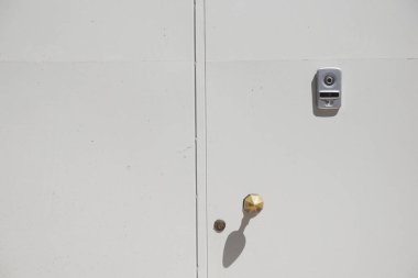 Beyaz bir ön kapıda altın bir kapı kolu ve gün ışığında parlak bir kilit var..