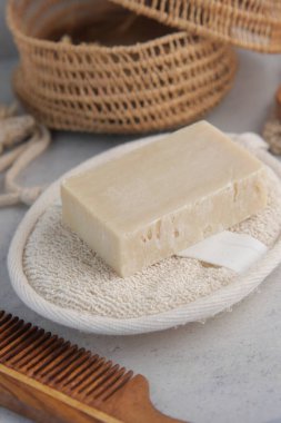 Basit bir sabun kalıbı yumuşak bir zemine yerleştirilmiş ve doğal aksesuarlarla çevrili..