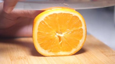 Tahta kesme tahtasındaki portakalı dilimleyen biri, sulu bölümler sergiliyor..