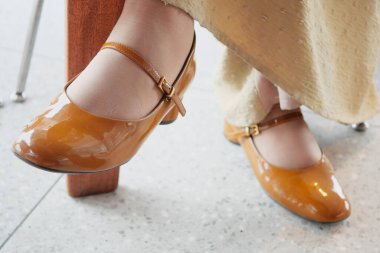 Kahverengi deri ayakkabılar bir kafede bir kadının zarif elbisesini güzelleştirir..