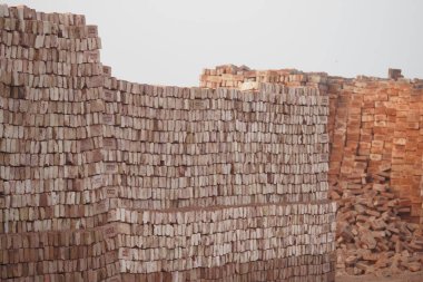 Yığılan tuğlalar gün ışığında bir şantiyede düzenlenir..