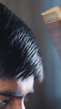 Genç bir insan sakin bir yerde ahşap bir tarak kullanarak saçlarını dikkatlice tarar..