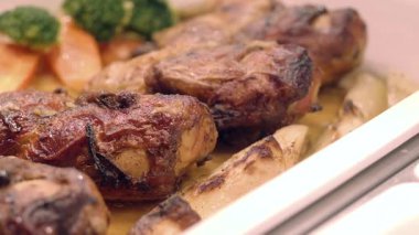 Sıcak bir mutfak ortamında taze sebzelerle servis edilen sulu kızarmış tavuk..