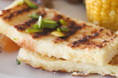 Bitkilerle süslenmiş ve dekoratif tabakta servis edilmiş ızgara ekmek dilimleri.. 