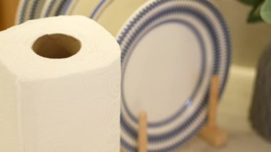 Kağıt havlu rulosu mutfak ortamında zarif tabakların yanında durur..