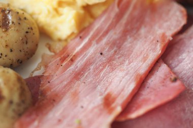 Yumurtalı ve dilimlenmiş etli kahvaltı tabağının yakından görüntüsü..