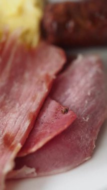 Bir tabakta dilimlenmiş çeşitli etlerin yakın plan görüntüsü, gösterişli doku.