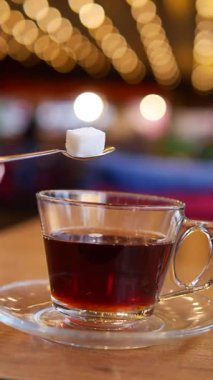 Bir insan sıcak bir atmosferde kaynayan bir fincan çaya şeker ekler..