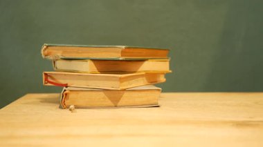 Eski bir kitap yığını basit bir arka planı olan ahşap bir masanın üzerinde duruyor..