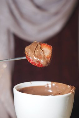 Arkadaşlarla bir toplantıda taze çileği zengin çikolataya batırmak..