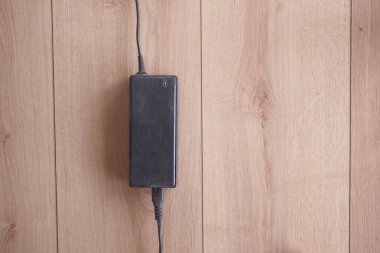 Siyah güç adaptörü hafif ahşap arka planda konumlandırıldı.