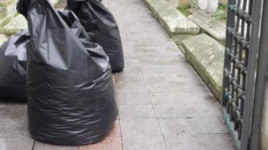 Mezarlığın yakınındaki kaldırım boyunca dizilmiş çöp torbaları toplanmaya hazır..