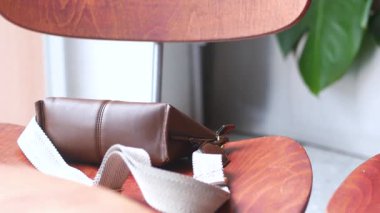 Deri bir kese, yeşillik eşliğinde ahşap bir sandalyeye konur..