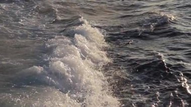 Güneş batarken dalgalar kıyı şeridi boyunca sorunsuzca akıyor..