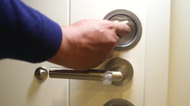 Bir el, koridordaki bir kapının kilidini açmak için anahtarsız bir giriş yastığını çalıştırır..