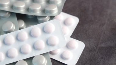 Çeşitli tabletler gri bir yüzey üzerinde ambalajlama içinde düzenlenir.