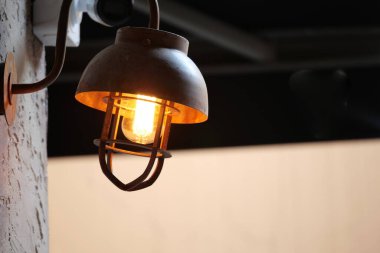 Sıcak metal bir lamba terasta hafifçe parlar, ambiyansı güçlendirir..