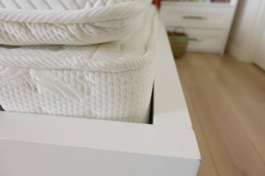 Yumuşak beyaz şilteler, parlak beyaz bir yatak çerçevesinde, rahat bir odada..