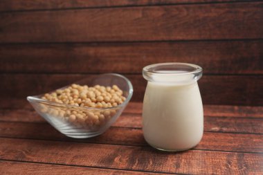 Taze soya sütü bir kase çiğ soya fasulyesinin yanında duruyor..