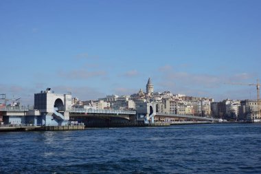 Galata Köprüsü, şehir binaları ve arka planda bir kuleyle suyu gerer..