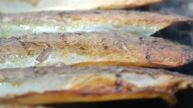 Balık filetolarını açık ateşte kızartıyorlar..